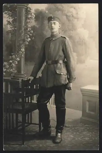 Foto-AK Junger Soldat mit Brille vor Fotokulisse, Uniformfoto, 1918