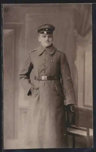 AK Junger Soldat mit Schirmmütze im Mantel, Uniformfoto