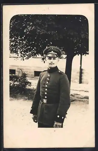 Foto-AK Soldat mit Schirmmütze vor einem Gebäude, Uniformfoto