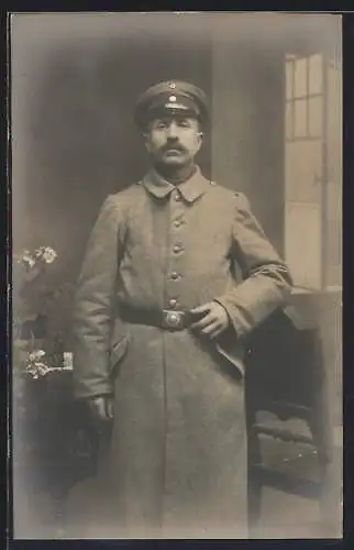 Foto-AK Soldat mit Schirmmütze u. Mantel, Uniformfoto