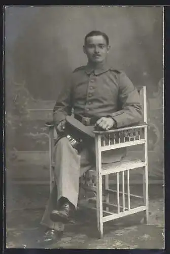 Foto-AK Soldat mit Schirmmütze vor einer Fotokulisse, Uniformfoto