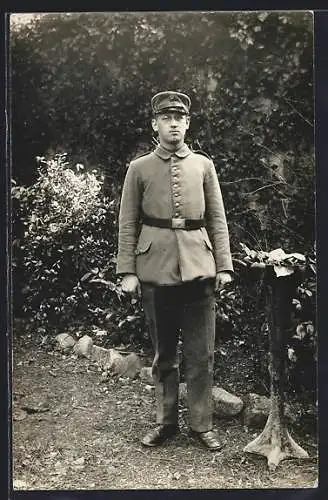 Foto-AK Soldat mit Schirmmütze in einem Garten, Uniformfoto, 1917