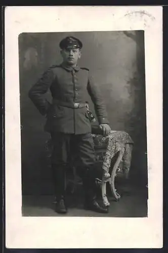 Foto-AK Soldat mit Schirmmütze vor einer Fotokulisse, Quaste, Uniformfoto