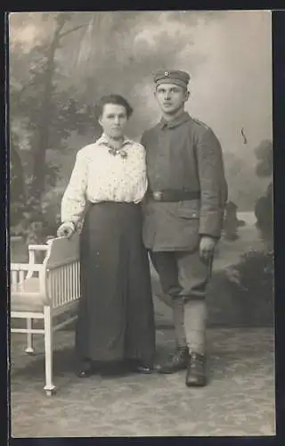 Foto-AK Soldat mit Braut vor einer Fotokulisse, Uniformfoto