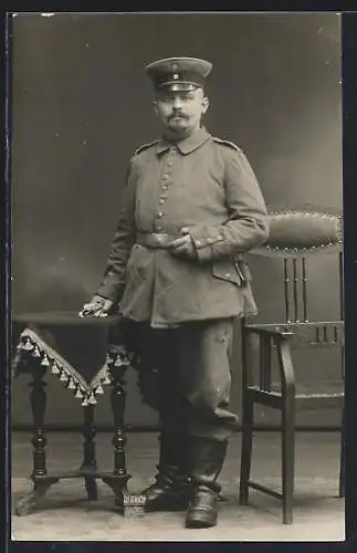 Foto-AK Soldat mit Schirmmütze und Handschuhen, Uniformfoto