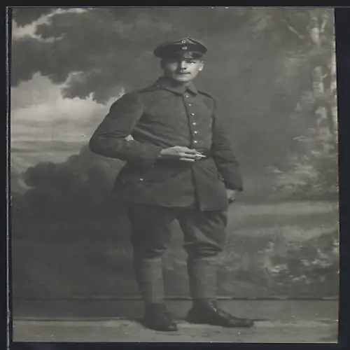 Foto-AK Soldat in Feldgrau Uniform mit Schirmmütze