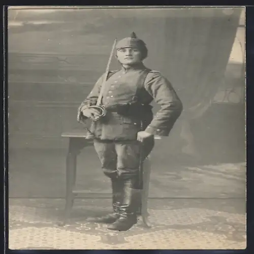 Foto-AK Soldat in Feldgrau Uniform mit Säbel, Magazintaschen und Pickelhaube