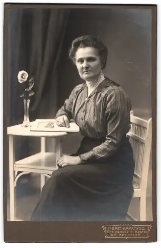 Fotografie Herm. Krausse, Steinbach /Erzgebirge, Am Bahnhof, Dame am Tisch mit Blume