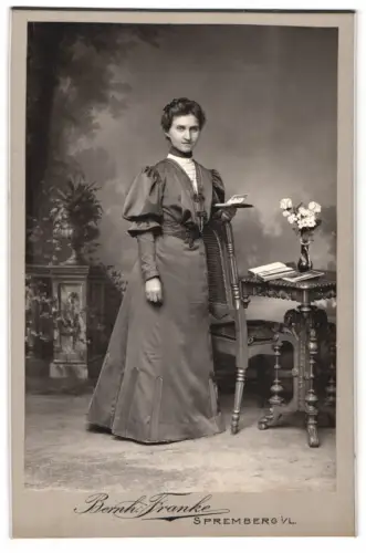 Fotografie Bernh. Franke, Spremberg, Elegante Dame neben Tisch mit Blumen