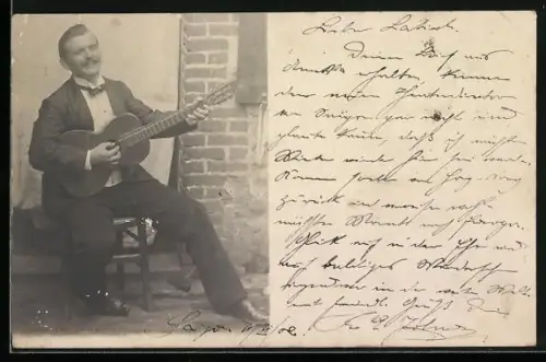 AK Mann sitzt auf einem Stuhl und spielt Gitarre
