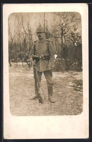 Foto-AK Soldat in Feldgrau Uniform mit Marschausrüstung, Pickelhaube und Gewehr