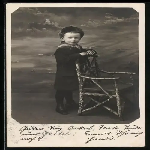 Foto-AK Kleiner Junge im Matrosenanzug am Stuhl in einer Studiokulisse