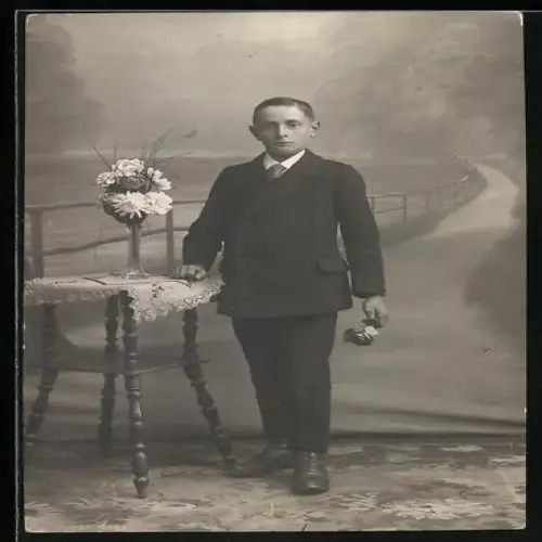 Foto-AK Junger Mann im Anzug mit Rose in einer Studiokulisse