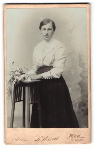 Fotografie K. Posselt, Ried, Elegantes Damenporträt mit Blumenstrauss