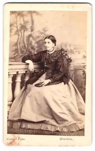 Fotografie Conrad Palm, München, junge Frau im hellen Reifrock mit dunkler Bluse vor einer Studiokulisse