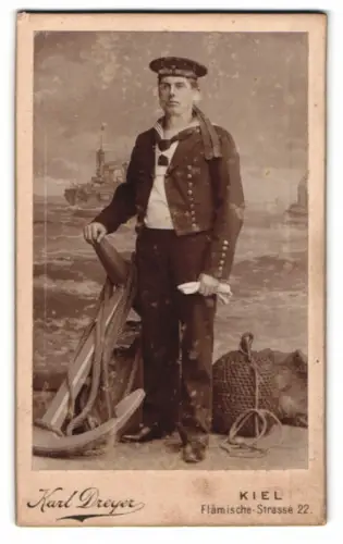 Fotografie Karl Dreyer, Kiel, Matrose in Uniform mit Mützenband Matrosen-Divison I. vor einer Studiokulisse