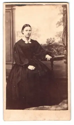 Fotografie G.M. Ollenborg, Wexio, CDV Eva Sjögren im dunklen Kleid vor einer Studiokulisse, 1865