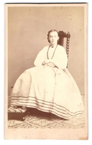 Fotografie unbekannter Fotograf und Ort, sitzende Dame in elegantem Kleid mit Perlenhalskette