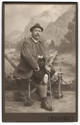 Fotografie M. Hauch, Prien, Porträt eines Mannes in traditioneller Tracht vor einer Studiokulisse