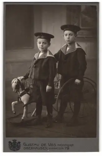 Fotografie Gustav de Vos, Oberhausen, Marktstr. 79, Zwei junge Knaben in Matrosenanzügen mit Spielzeugpferd samt Gespann