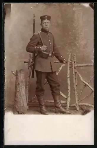 Foto-AK Einjährig-Freiwilliger in Uniform mit Gewehr und Krätzchen