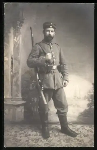 Foto-AK Soldat in Feldgrau Uniform mit Koppeltaschen, Gewehr und Krätzchen