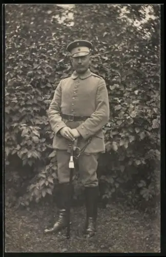 Foto-AK Soldat in Feldgrau Uniform mit Säbel und Schirmmütze
