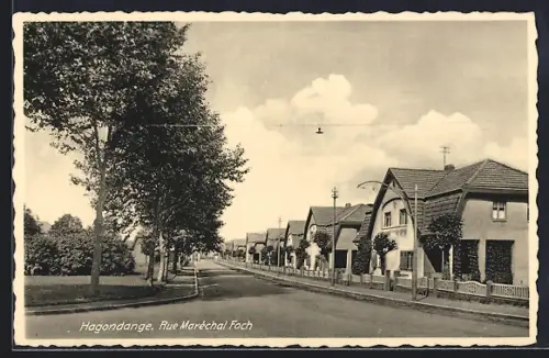 AK Hagondange, Rue Maréchal Foch avec maisons alignées et arbres bordant la route