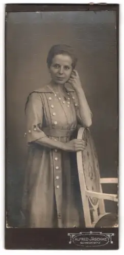 Fotografie Alfred Jäschke, Schedewitz, Frau in karirtem Kleid neben Stuhl