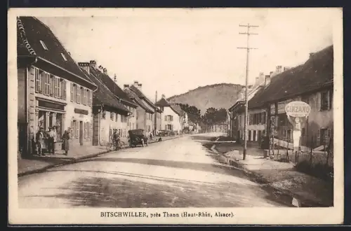 AK Bitschwiller près Thann, Rue principale avec bâtiments et colline en arrière-plan