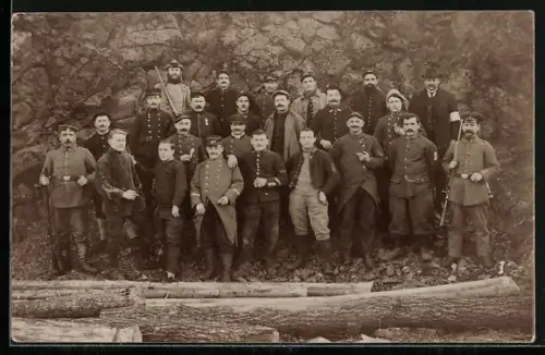 Foto-AK Kriegsgefangene mit Bewachern vor einer Felswand, Gruppenfoto
