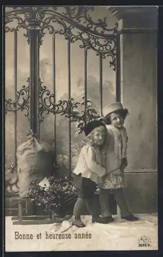 Foto-AK R & K / L Nr. 3943/4: Zwei Kinder mit einem Schlitten vor einem Tor, Bonne et heureuse année