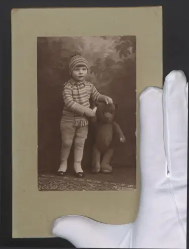 Fotografie junger Knabe mit seinem grossen Teddybär, Winterkleidung
