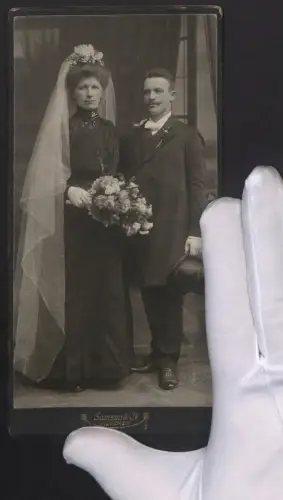 Fotografie Samson & Co., München, bayerisches Brautpaar im schwarzen Hochzeitskleid und Anzug mit Zylinder