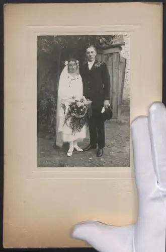 Fotografie L. Forstner, Mistelbach, oberfränkisches Brautpaar im Hochzeitskleid mit Brautstrauss und im Anzug, 18 x 28cm