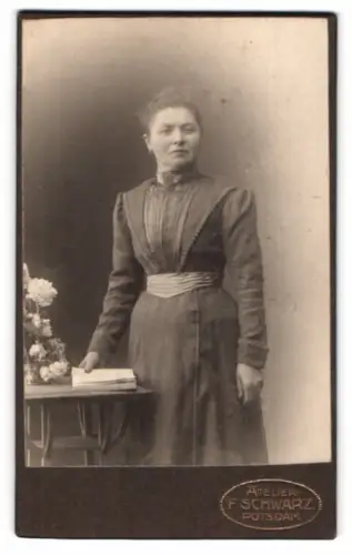Fotografie F. Schwarz, Potsdam, Brandenburgerstr. 49/52, Dame stehend an Tisch mit Blumen 1905