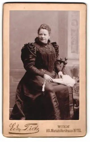 Fotografie Edm. Tietz, Wien, Mariahilferstrasse 110, Sitzende Frau mit elegantem Kleid