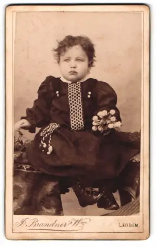Fotografie J. Brandner, Leoben, Badehaus, Porträt eines kleinen Kindes mit Blumenstrauss