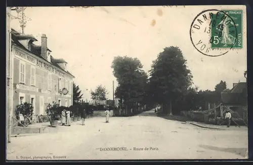 AK Dannemoine, Route de Paris avec passants et bâtiments