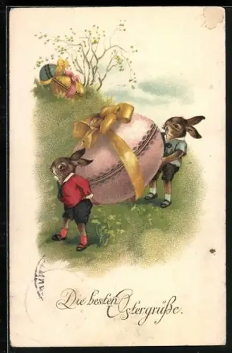 Künstler-AK Zwei Osterhasen tragen ein riesiges Osterei einen Hügel hinunter