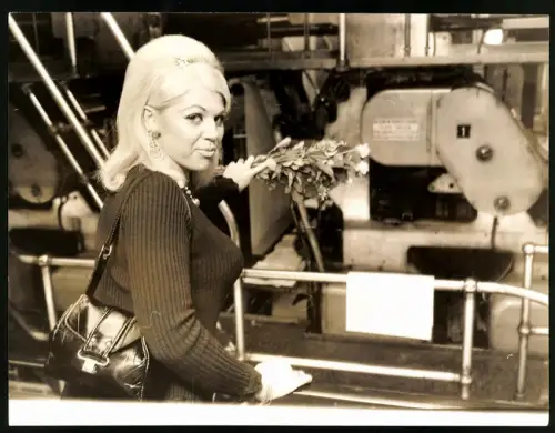 Fotografie Ulf Schneider, dralle Blondine mit modischer Frisur legt Grabstrauss vor einer Maschinenanlage ab