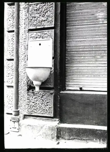 Fotografie Waschbecken an einer Gebäudefassade neben Schaufenster installiert