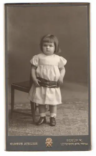 Fotografie Globus Atelier, Berlin, Leipziger Str. 132/137, Kind in weissem Kleid neben Stuhl
