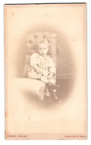 Fotografie Emma Holm, Carlscrona, Kleines Kind auf gepolstertem Stuhl