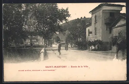 AK Saint-Martory, Entrée de la ville avec rue bordée d`arbres et bâtiments anciens