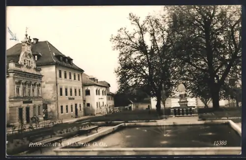 AK Reichenthal im Mühlkreis, Verhülltes Denkmal und Wasserbecken, Ansicht mit Strasse u. Volksschule, Ziergiebel-Haus