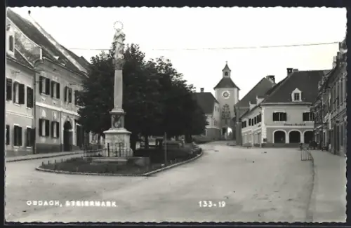 AK Obdach, Platz mit Denkmal und Blick auf Stadttor, Häuserfassaden mit Geschäften
