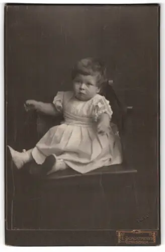 Fotografie E. Schultheiss, Gernsbach, Sitzendes Kleinkind in festlichem Kleid