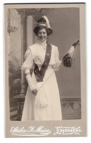 Fotografie J. Maier, Ebersberg, Dame zum Carneval mit Ulanen Tschapka, Schärpe und Fähnchen, 1911