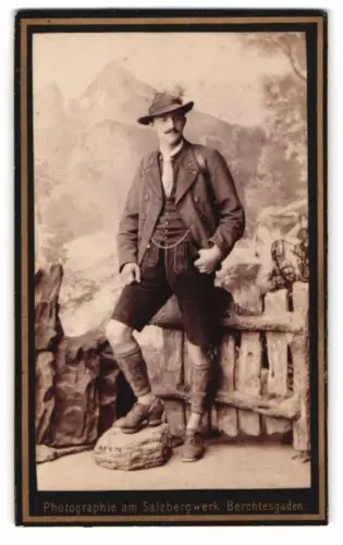 Fotografie P. Ney, Berchtesgaden, junger Bayer in Tracht mit Lederhose mit Gamaschen vor einer Studiokulisse